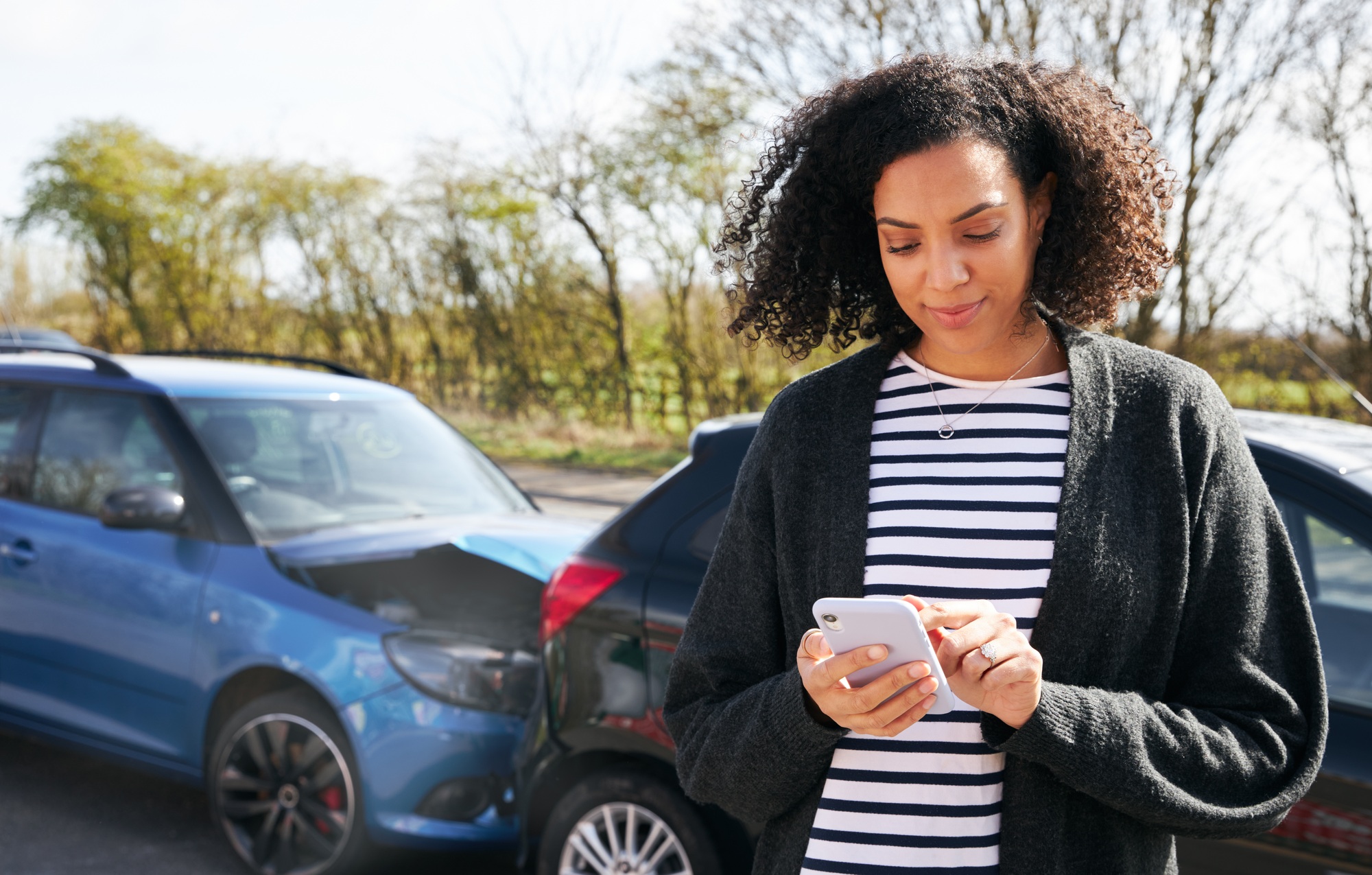 Female Driver Contacting Car Insurance Company On Mobile Phone After Road Traffic Accident
